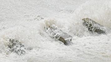 A row of chute dentate blocks in concrete water spillway channel slope slowing down splashing flow of water running down 2 video