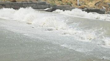 row of chute dentate blocks in concrete water spillway channel slope slowing down splashing flow of water running down 3 video