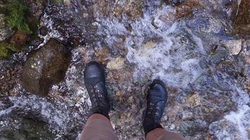 legs in ankle boots standing in shallow mountain creek, view from above.. video