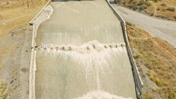 row of chute dentate blocks in concrete water spillway channel slope slowing down splashing flow of water running down 6 video