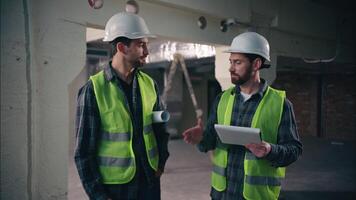 Two joyful smiling Caucasian architects guys colleagues men technicians talking conversation males builders coworking mechanics shake hands handshake teamwork in construction workers partnership plan video