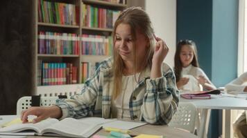 Bored sad frustrated teen kid Caucasian girl pupil schoolgirl upset learner at desk tired lazy exhausted student child studying lesson reading boring book learning in classroom school study textbook video