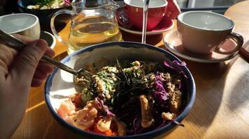 disfrutar un vistoso cuenco de sano ensalada acompañado por té en brillante café ajuste video