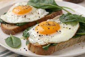 Fried Eggs on Toast with Fresh Spinach and Black Pepper photo