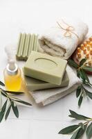 Olive oil soap, essential oil and white towels creating relaxing spa setting photo