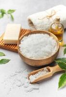 Magnesium flakes in a wooden bowl with soap, towel and essential oil creating a relaxing spa scene photo