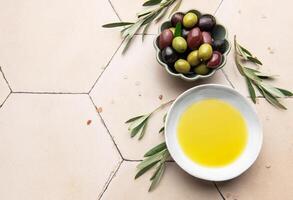Oil and olives with olive branches resting on a tiled surface photo
