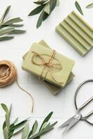 Natural olive soap bars with twine and scissors on white tile background photo