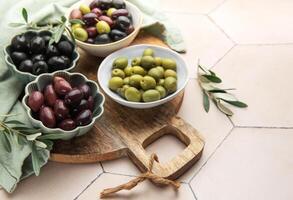 Green, black and kalamata olives in bowls on table photo