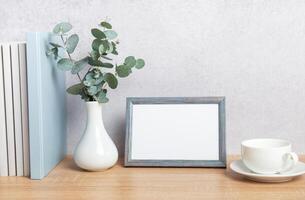 Eucalyptus branches, empty frame and coffee cup creating cozy atmosphere on wooden table photo