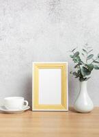 Empty frame, coffee cup and eucalyptus branches on table photo
