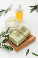 Natural olive soap, moisturizing cream and olive branches creating relaxing spa scene photo