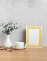 Eucalyptus branches, coffee cup, eyeglasses and empty frame creating cozy atmosphere on table photo