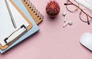 Workspace organizing accessories on pink table with plant and keyboard photo