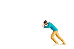 Miniature Figurine Pushing Against Invisible Force isolated on a white background with clipping path photo