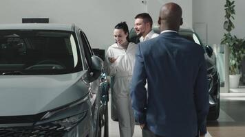 A car sales manager shows a vehicle to a couple clients in a luxurious dealership. Concept a premium car-buying experience that combines expert guidance with high-end service in an elegant setting video