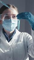 uma cientista dentro protetora engrenagem examina uma teste tubo dentro uma moderno laboratório, destacando avanços dentro médico pesquisa e a em andamento desenvolvimento do crucial vacinas para público saúde video