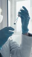 A focused scientist in a white lab coat and blue gloves prepares a vaccine by extracting liquid from a vial in a sunlit lab, highlighting the importance of essential medical research video