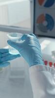 dentro uma ocupado laboratório, uma focado cientista dentro uma laboratório casaco e luvas estudos uma brilhante azul solução dentro uma taça, cercado de teste tubos, destacando a ativo pesquisa em crucial vacina desenvolvimento video
