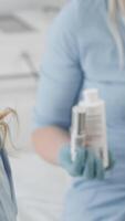 In a bright and sterile medical setting, a patient engages in a detailed consultation with a professional cosmetologist about skincare, showcasing an effective product while discussing skin health video
