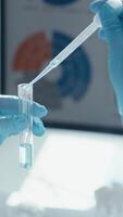 A scientist in a lab, wearing gloves, is using a pipette to transfer liquid into a test tube, demonstrating the precise techniques needed for scientific research and experimentation video