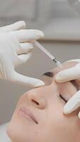 The image shows a skilled medical professional administering a botulinum injection near a patients eyebrows to reduce wrinkles and enhance overall beauty in an aesthetic procedure video