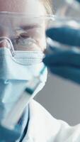 In a modern lab, a focused scientist in protective gear meticulously examines a vaccine syringe, demonstrating their careful approach to essential research in healthcare and immunization video