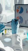A scientist in a lab coat and gloves conducts vital vaccine research, carefully examining a test tube and analyzing complex data on a monitor, highlighting the importance of their work for healthcare video