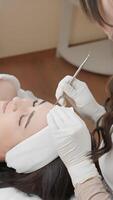 un expérimenté cosmétologue effectue une précis faciale traitement sur une satisfait client, en utilisant Avancée soin de la peau techniques dans une calme clinique, promouvoir bien-être, relaxation, et soin de la peau santé video