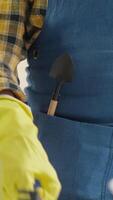 A detailed closeup view showcasing various gardening tools neatly arranged in a blue apron pocket, featuring essential hand trowels, all set against a backdrop of vibrant houseplant care settings video