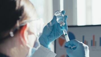 In a busy lab, a scientist in a white coat carefully prepares a vaccine with a vial and syringe, demonstrating the meticulous nature of scientific research in a modern lab setting video