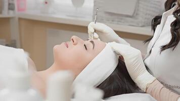 A skilled cosmetologist is performing a detailed cosmetic procedure on a clients face using specialized tools in a serene spalike environment that promotes relaxation and wellness video