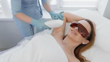 A skilled cosmetologist conducts a laser hair removal treatment on a clients underarms, ensuring they wear protective eyewear for safety and comfort, guaranteeing optimal results video