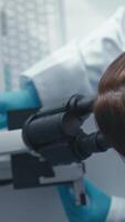 In a lab, a focused scientist examines samples under a microscope, while monitor data visualizations illustrate complex research, emphasizing the importance of innovation in science video