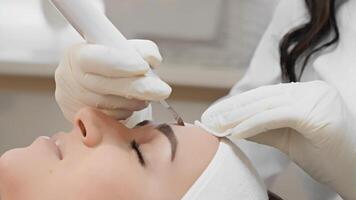 A highly skilled and experienced cosmetologist at a wellknown and respected clinic is using a stateoftheart device on a clients forehead during an extensive and detailed skin treatment session video