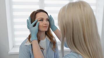 A skilled cosmetologist carefully evaluates a clients unique facial features during a detailed beauty consultation, demonstrating utmost professional care in a modern and inviting clinic setting video