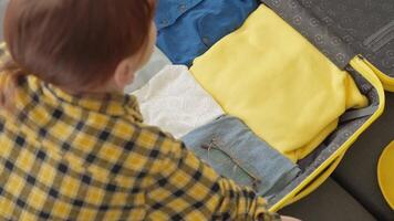 A diligent person packs a yellow suitcase with clothes, shoes, and a camera, demonstrating organization for an exciting adventure and a hasslefree trip filled with unforgettable experiences video