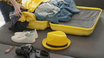 An enthusiastic person is joyfully packing a bright yellow suitcase with colorful clothes and accessories for an exciting travel adventure filled with exploration and new experiences video