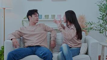 Asian couple arguing on sofa at home, husband blaming upset wife, family concept video