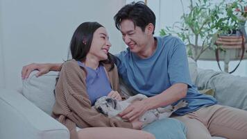 A young couple sits comfortably on the floor of their modern living room, smiling as they interact with their smartphone while their dog rests between them creating a cheerful atmosphere video