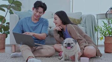 Couple enjoying at home couple sits comfortably on the floor of their modern living room, smiling a dog rests between them, creating a cheerful atmosphere. video