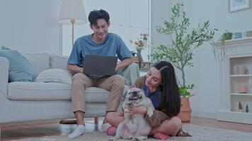 Couple enjoying at home A young couple sits comfortably on the floor of their modern living room, smiling a dog rests between them, creating cheerful atmosphere. video