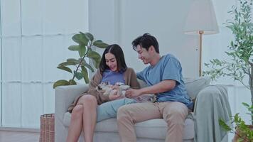 A young couple sits comfortably on the floor of their modern living room, smiling as they interact with their smartphone while their dog rests between them, heerful atmosphere. video