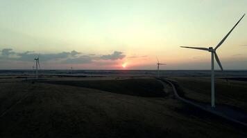 Windmills generating electric power in a serene windmill park at sunset, showcasing green energy in action video
