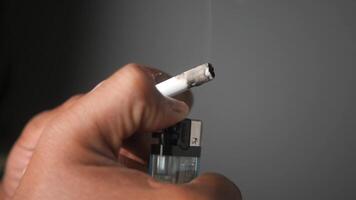Hand holding a cigarette and lighter in a dimly lit space video