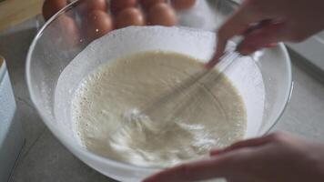 Hand using whisk to mix raw egg into pancake batter video