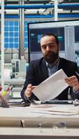 Vertical Business executives meet with investors to discuss the integration of automation technology in solar panel production processes, looking over paperwork and schematics, camera A video