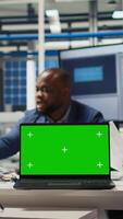 Vertical Factory engineers study schematics, refining production layouts using chroma key laptop. Experts outlining industrial plant configurations for prototypes using isolated screen notebook, camera A video