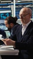 Vertical Industrial plant senior manager looking over paperwork files. Elderly factory executive reading documents, meeting with investors to discuss automating production, camera A video