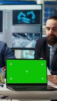 Vertical Factory engineers study schematics, refining production layouts using chroma key laptop. Experts outlining industrial plant configurations for prototypes using isolated screen notebook, camera B video